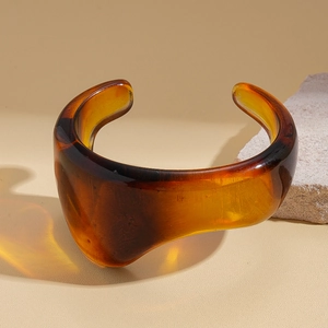 Macro detail of amber acrylic open bangle showing the smooth translucent resin texture