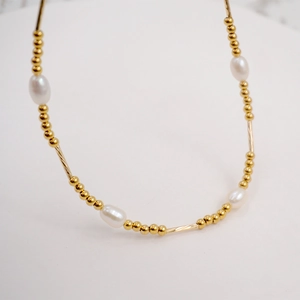 French vintage freshwater pearl necklace with golden beads on a white background
