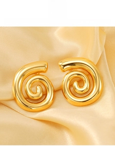 Dettaglio di orecchini a spirale in titanio con finitura oro 18k lucido su seta
