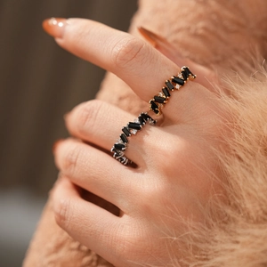 Detail showing gold and silver rings with black rectangular zircon on brown plush
