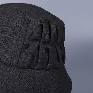 Detailed macro shot showing vertical pleats on a black linen sun hat for women