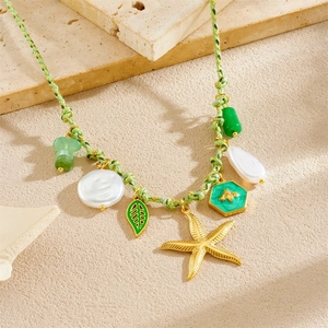 Green woven necklace with golden starfish, baroque pearl and jade charms on stone