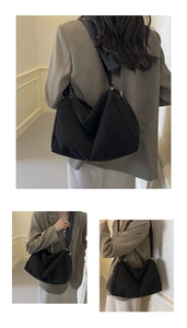 Detail view showing a large capacity black suede baguette bag with wide shoulder straps