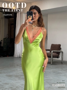 Detail of green satin dress with orange lace V-neckline and silky fabric texture