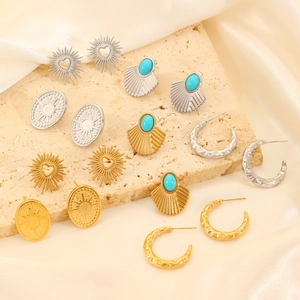 Detailed close-up of textured gold and silver earrings on stone and silk background