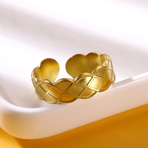 Macro shot of gold-plated cross ring with rhombic texture on a white ceramic tray