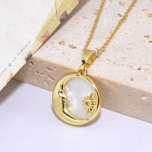Detail of gold star and moon pendant necklace with white shell inlay and zircon stone
