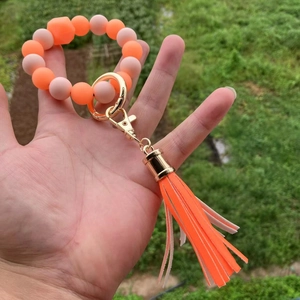 Dettaglio ravvicinato del bracciale con perline in silicone arancione e rosa e nappa vivace
