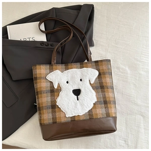 Detail of checkered tote bag featuring a plush dog embroidery and brown leather trim