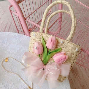 Handmade straw woven bag with pink tulips, satin bow, and pearls on a lace tablecloth