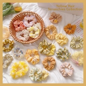 Collection of yellow hair scrunchies with floral and plaid patterns in a woven basket
