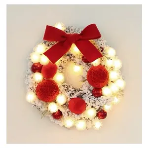 Detail of white flocked Christmas wreath with red bows, ornaments and warm LED lights