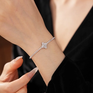 Detail view of a sparkling cubic zirconia clover bracelet on a woman wrist with silver finish