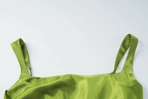 Detail view of the green satin bodice with elegant straps and glossy fabric texture
