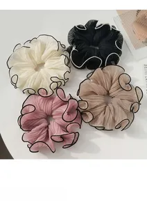 Close-up of four oversized chiffon scrunchies in cream, black, pink, and brown with contrast edges