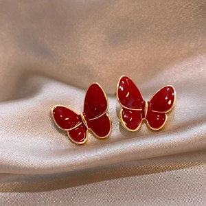 Elegant red butterfly stud earrings with gold metal edges on silk background