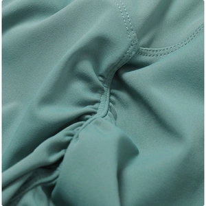 Close-up of teal high-elastic yoga pants featuring flatlock stitching and ruched fabric texture