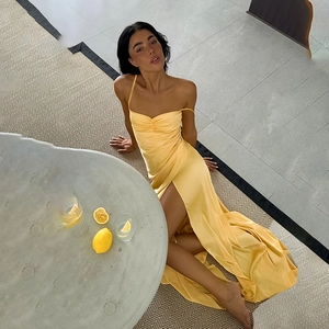 Detail of yellow satin evening dress with high slit and elegant spaghetti strap design