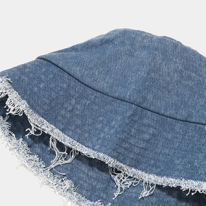 Vue macro des bords effilochés et de la texture en sergé du bob en jean bleu clair