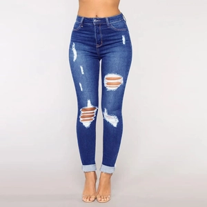Detail of dark blue high-waist skinny jeans featuring distressed ripped knees and cuffed hems