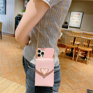 Pink PU leather crossbody phone case with heart buckle and gold chain strap shown on model