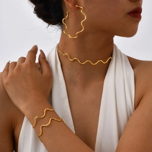 Detail of 18K gold plated wavy jewelry set including choker, earrings and bracelet on model