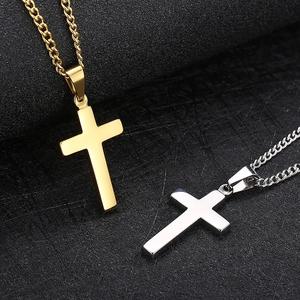 Gros plan de colliers croix en acier inoxydable or et argent sur texture noire