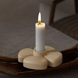 Modern beige flower candle holder with white pillar candle on a dark wood stand