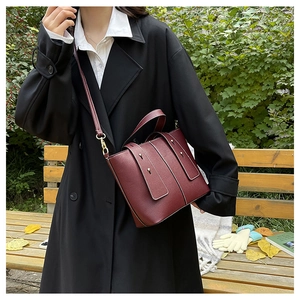 Vintage burgundy lychee leather tote bag with gold accents in an elegant autumn setting