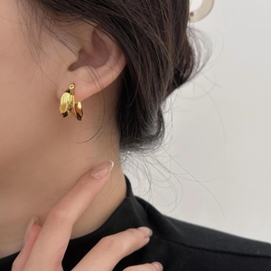 Close-up of elegant gold twisted U-shaped earrings worn by a model in profile view