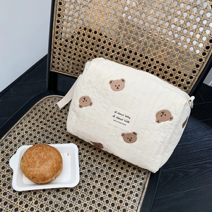 Detailed view of quilted cotton stroller bag with cute brown bear embroidery and canvas strap