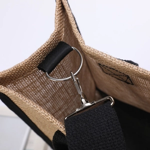 Durable brown jute tote bag detail featuring black fabric strap and silver metal hook