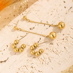 Minimalist gold ball drop earrings and C-shaped beaded stud set on stone background