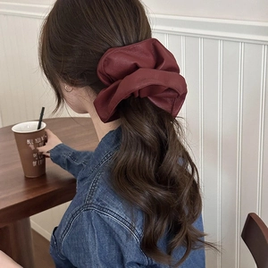 Elegant wine red leather hair scrunchie with pleated texture shown in hair