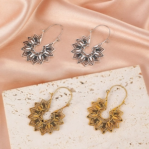Détails de boucles d'oreilles fleuries bohèmes en or et argent sur des fonds texturés raffinés