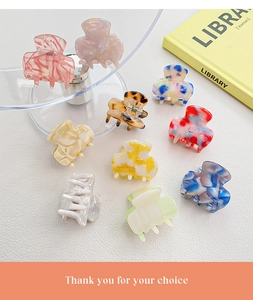 Collection of various acetate hair claws in marble and floral patterns on white texture