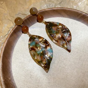 Retro tortoise shell leaf drop earrings with amber resin texture on white linen