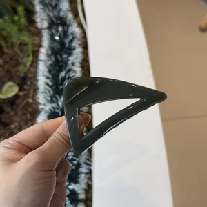Detail of a dark green triangular hair claw clip with a polished finish and elegant design