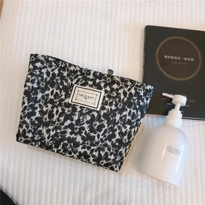Detailed view of black and white floral jacquard cosmetic bag with quilted texture