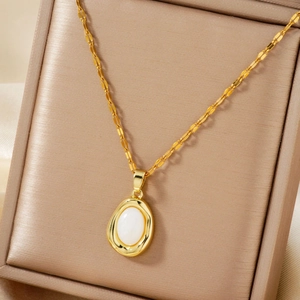 Close-up of a gold oval pendant necklace with a white gemstone in a jewelry box