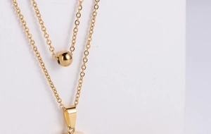 Detailed macro view of the double-layered gold necklace with polished round bead charm