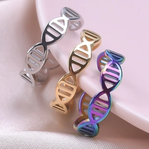 Three DNA helix design rings in silver, gold and rainbow colors on pink silk fabric