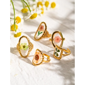 Detailed close-up of gold sunflower resin rings with dried flowers on white fabric