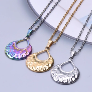 Three minimalist teardrop pendants with hammered texture in gold, silver, and rainbow colors