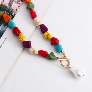 Detail of bohemian necklace with colorful gemstone beads and a baroque pearl drop charm