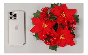 Detail of red poinsettia and berries Christmas wreath showing size relative to a phone