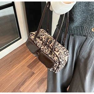 Detail of leopard print shoulder bag featuring faux leather trim and dual front pockets