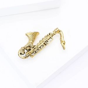 Detailed close-up of golden saxophone brooch with enamel finish on white pedestal