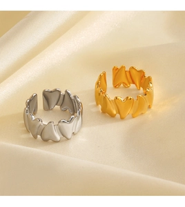 Detail of interlocking heart-shaped gold and silver open rings on beige silk fabric