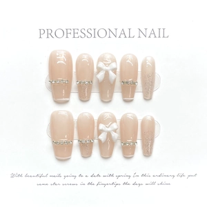 Close-up of pink press-on nails with 3D white bows and silver rhinestones detail